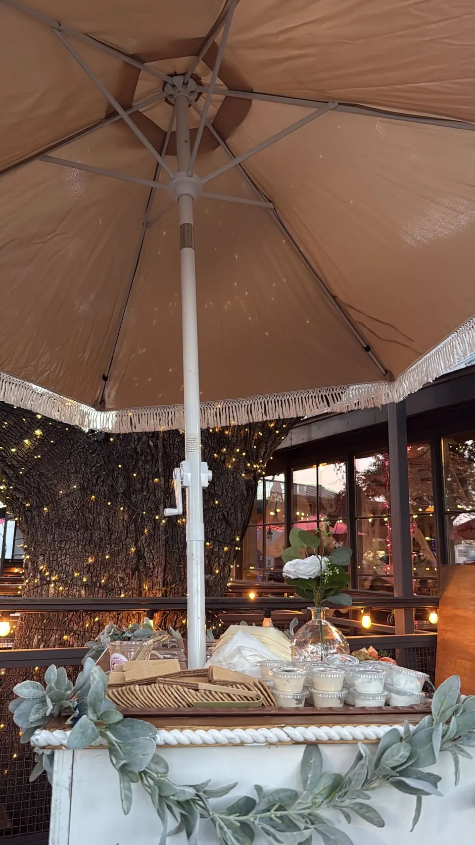 A decorated refreshment cart beneath an umbrella and twinkling lights
