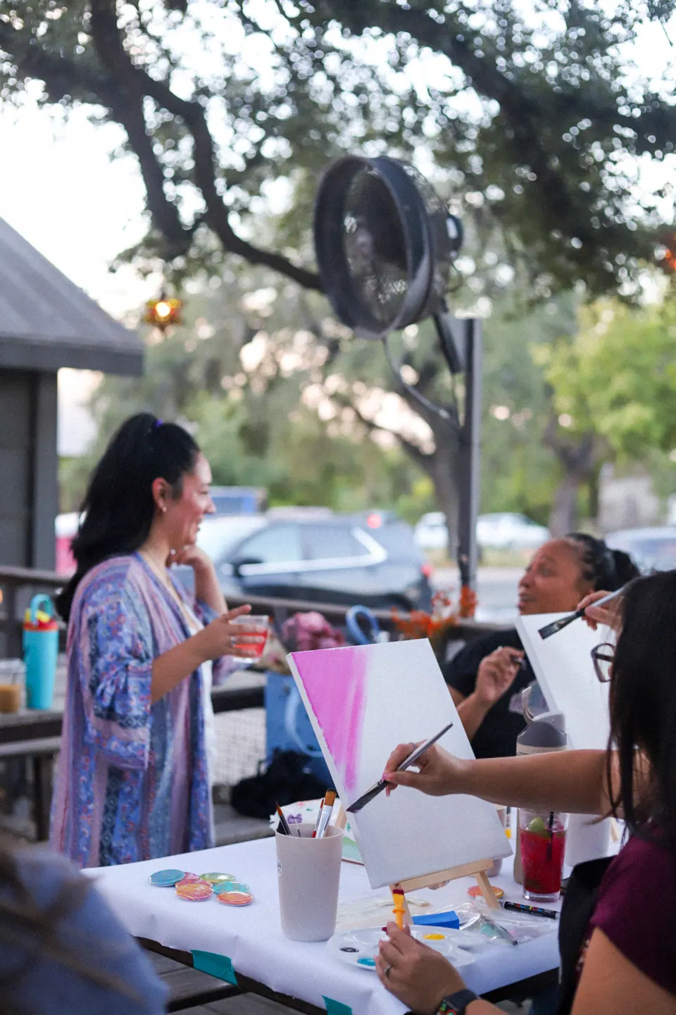 Guests painting and chatting around an outdoor table